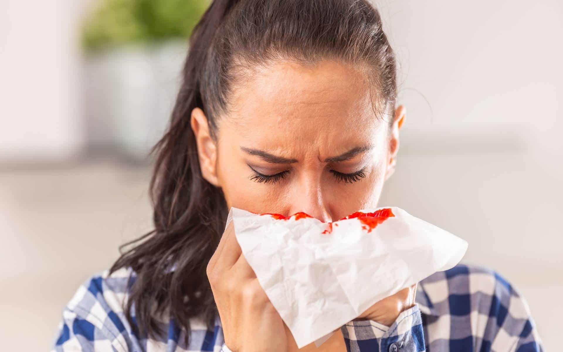 Uma mulher detendo um sangramento nasal com um lenço de papel.