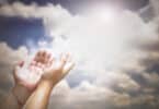 Uma pessoa estendendo suas mãos ao céu.