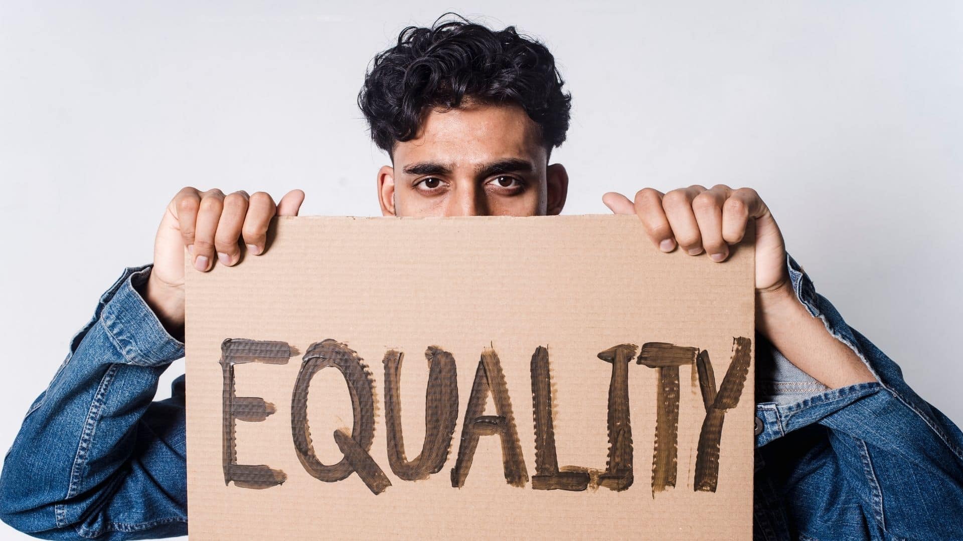 Um homem segurando uma placa de papelão escrita "equality".