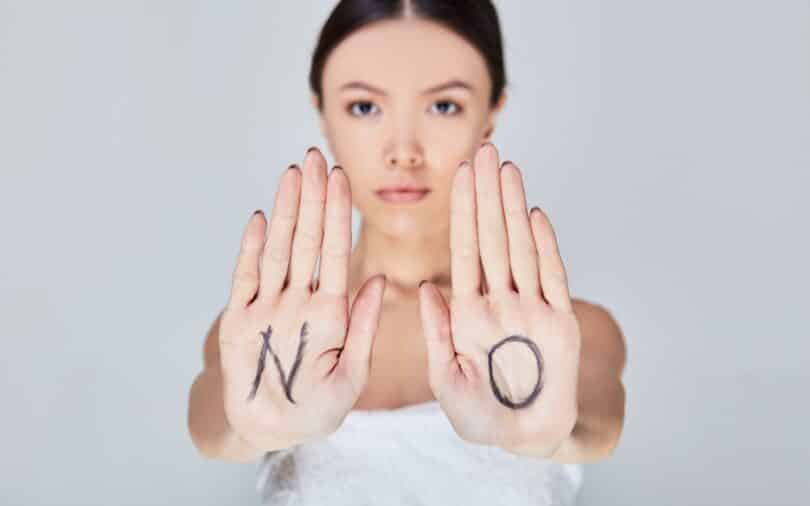 Uma mulher exibindo suas palmas da mão. Ambas constituem a palavra "NO", do inglês.