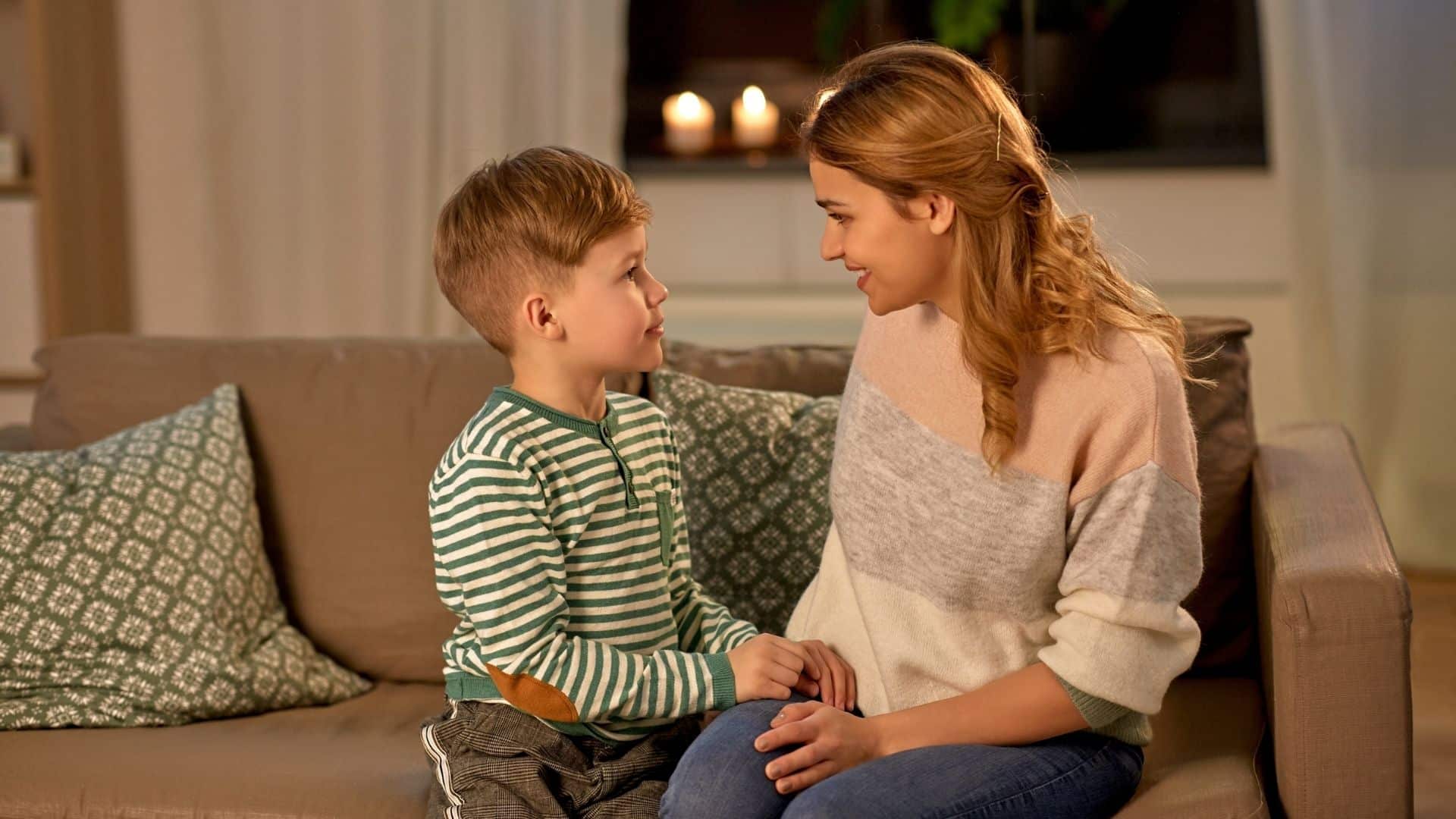 Uma mulher e uma criança conversando sentados num sofá.