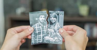 Duas mãos unindo fragmentos de uma mesma fotografia. Cada parte de um fragmento contém um membro de um casal conjugal amoroso.