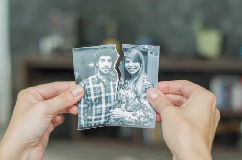 Duas mãos unindo fragmentos de uma mesma fotografia. Cada parte de um fragmento contém um membro de um casal conjugal amoroso.