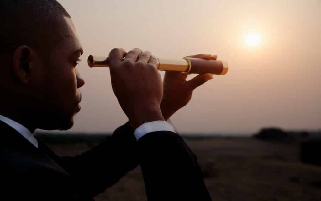 Um homem utilizando uma luneta para visualizar o horizonte.