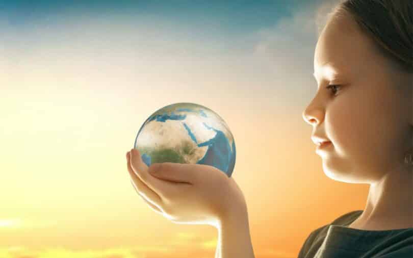 Uma pequena criança observando um globo terrestre em suas mãos.