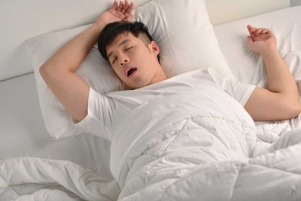Um homem asiático roncando ao dormir.