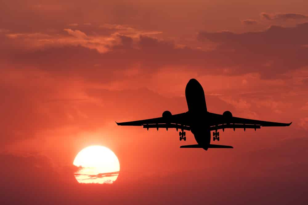 Avião sobrevoando em um céu avermelhado.