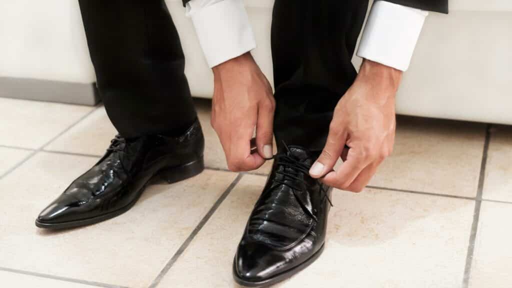 Um homem calçando um par de sapatos pretos.