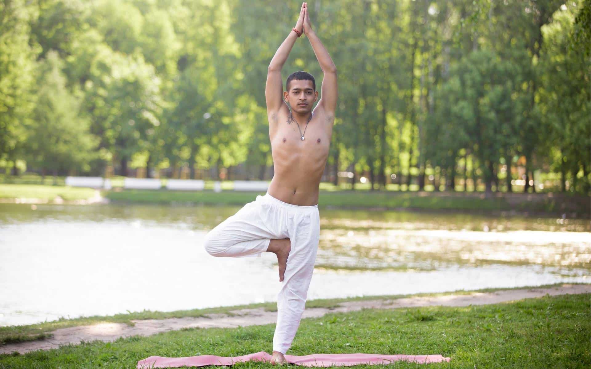 Um homem realizando a postura da árvore, do Yoga.