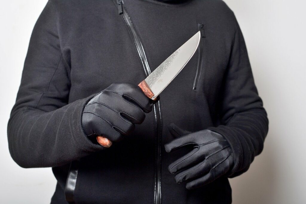 Homem de luvas, segurando uma faca.