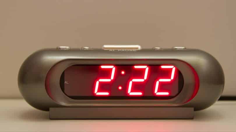 Relógio digital com a hora 2:22 em vermelho.
