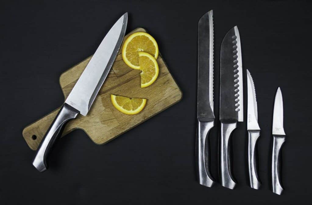 Conjunto de facas dispostas em uma mesa. Ao lado há uma tábua com limões cortados.
