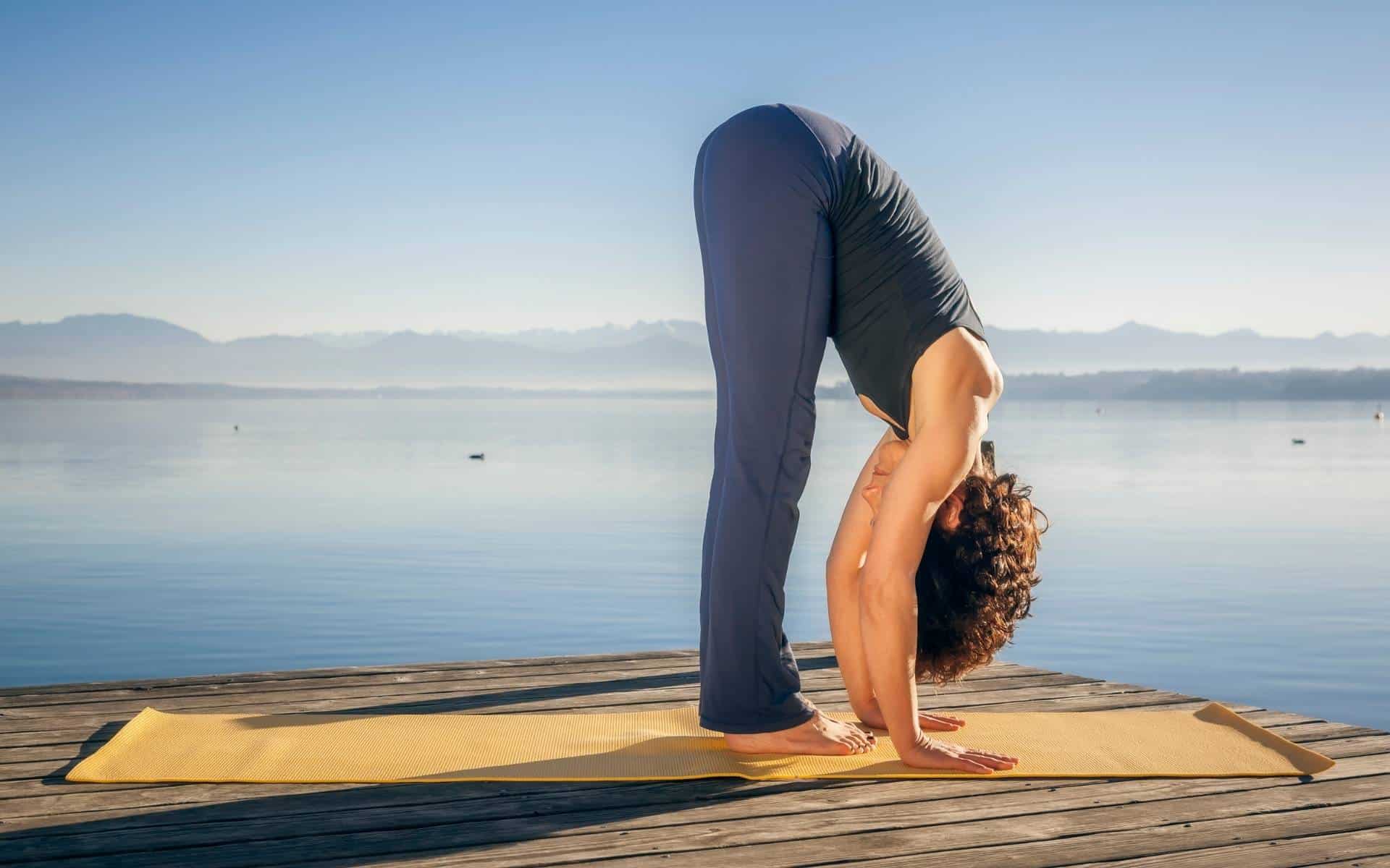 Uma mulher realizando a posição Uttanasana do Yoga.