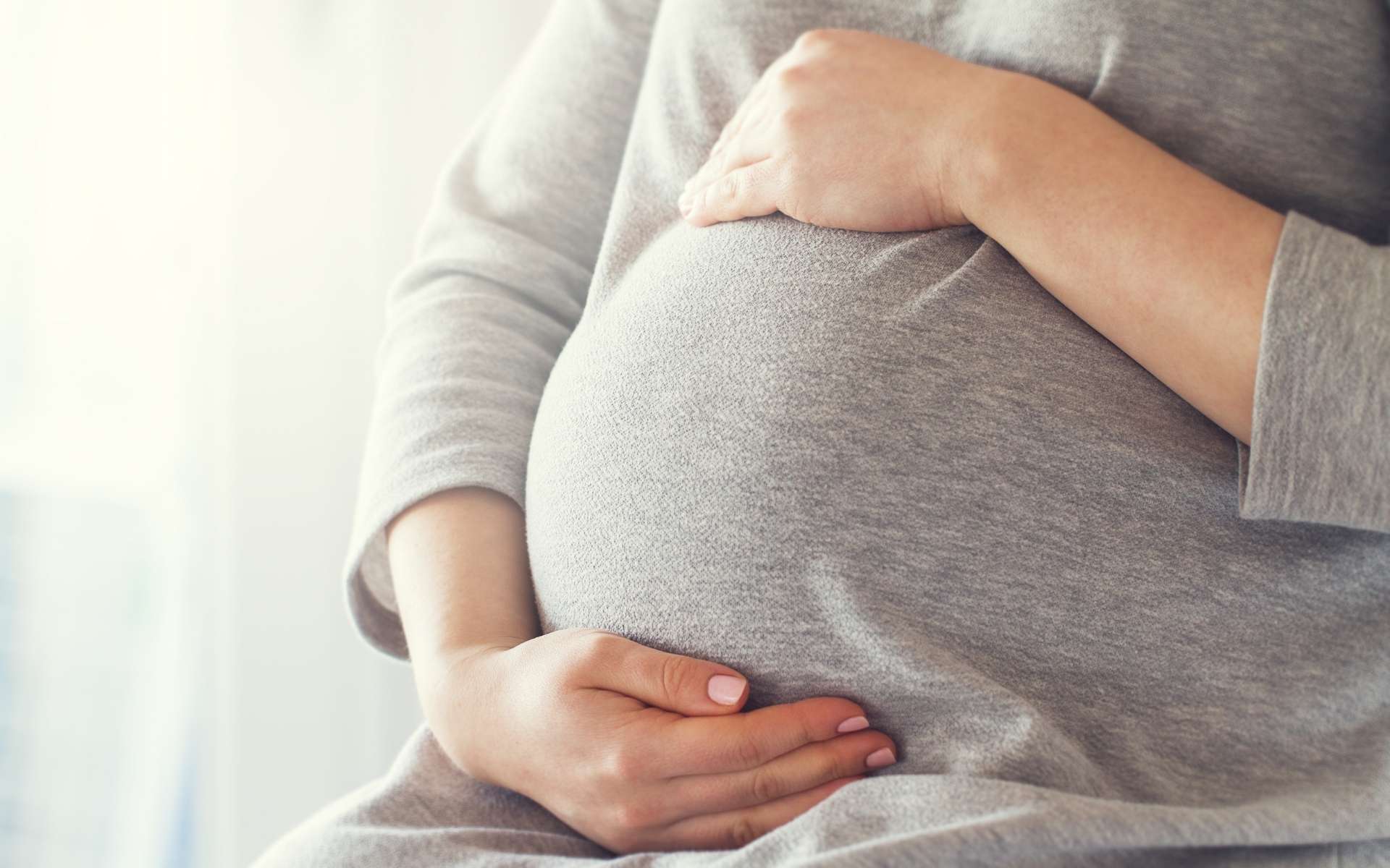 Uma mulher grávida acariciando sua barriga.