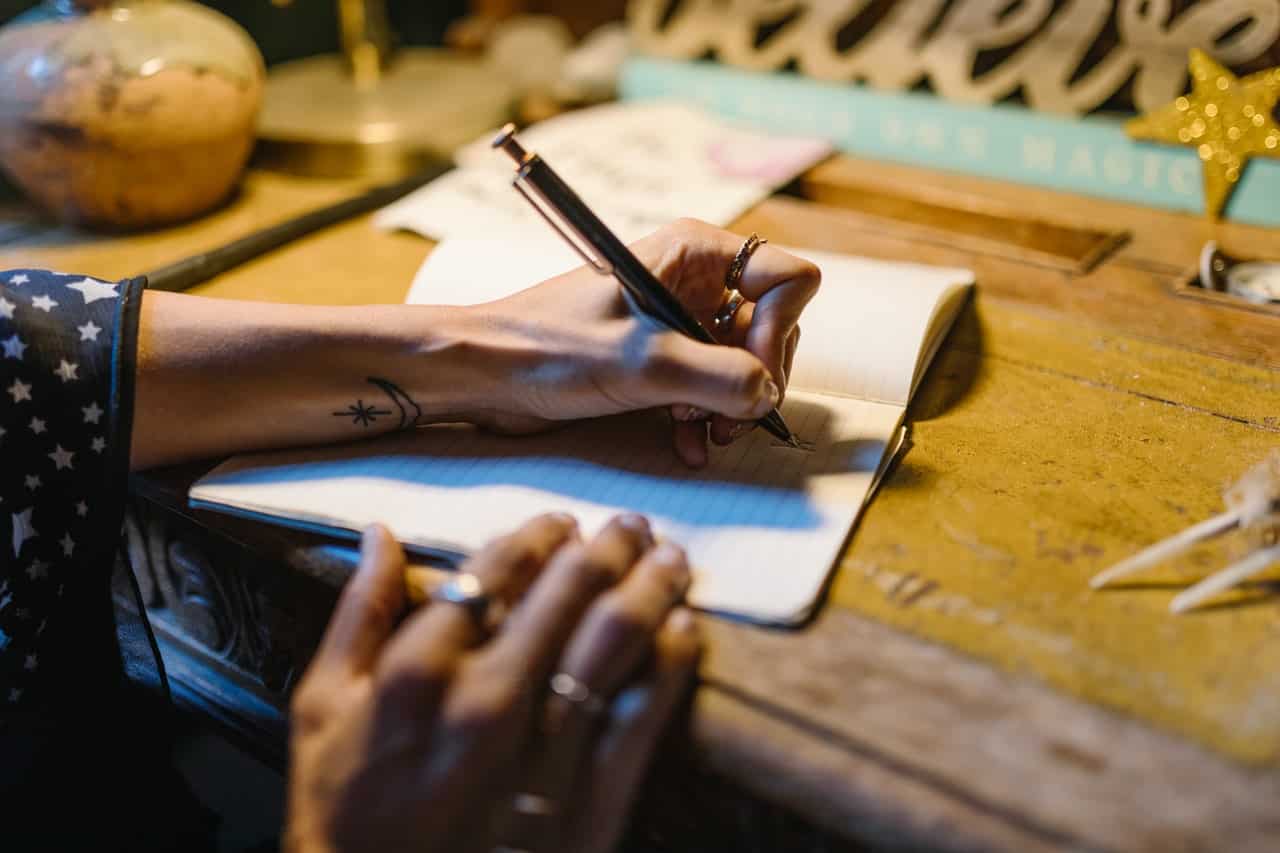 Mãos femininas escrevendo em um caderno.