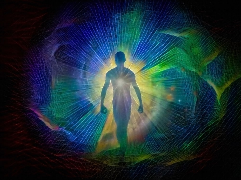 Silhueta de homem em pé entre feixes de luz coloridos e com uma luz branca brilhante no centro de seu peito