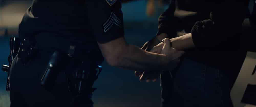 Policial prendendo as mãos de uma pessoa atrás das costas em algemas
