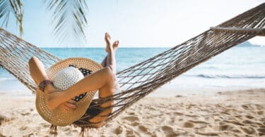 mulher deitada em uma rede na praia.