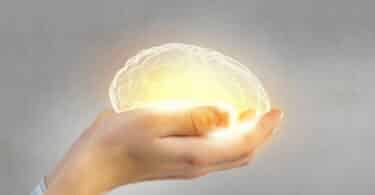 Pessoa segurando um cérebro brilhando em suas mãos, representando os cuidados que devemos ter com nossa mente