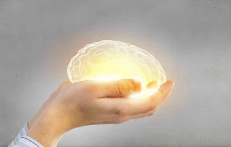 Pessoa segurando um cérebro brilhando em suas mãos, representando os cuidados que devemos ter com nossa mente