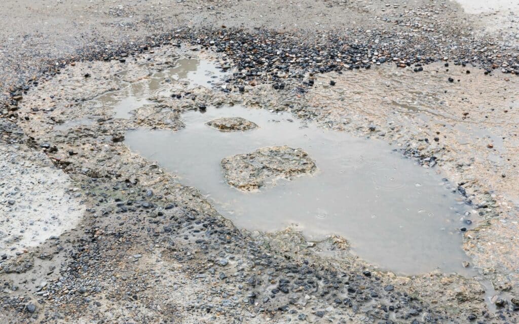 Numa rua, um buraco com água.