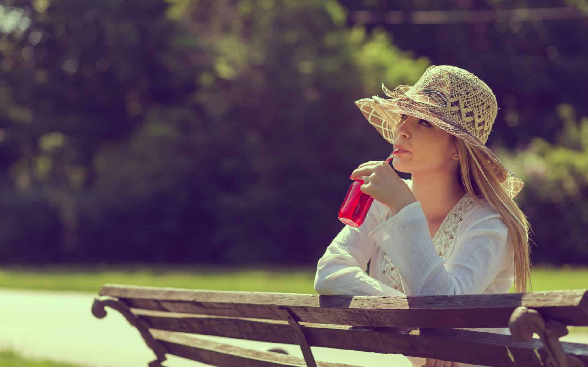 Uma mulher tomando um copo de refresco em meio à uma praça.