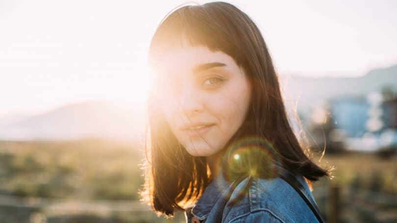 Um raio de luz solar incidindo sobre uma mulher que sorri.