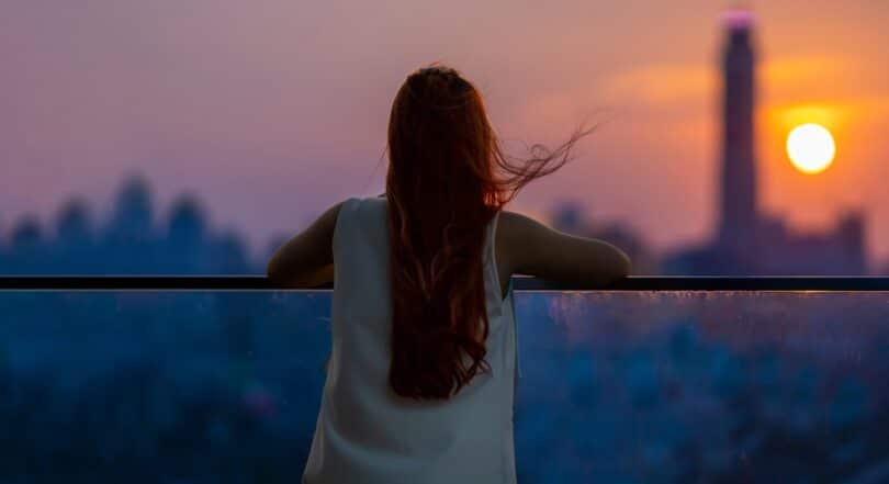 Uma mulher observando um pôr do sol.