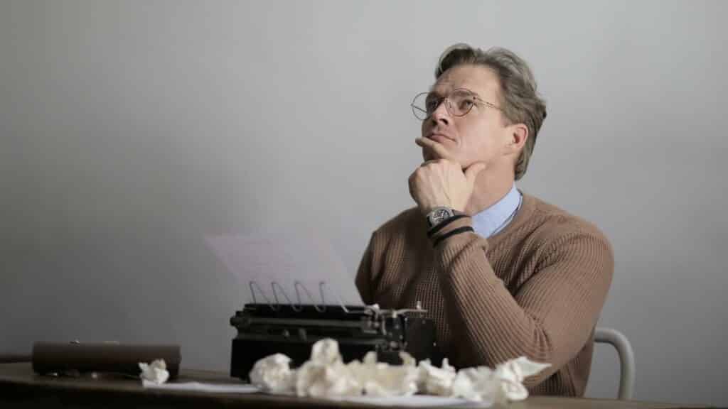 Um homem pensativo a utilizar uma máquina de escrever.