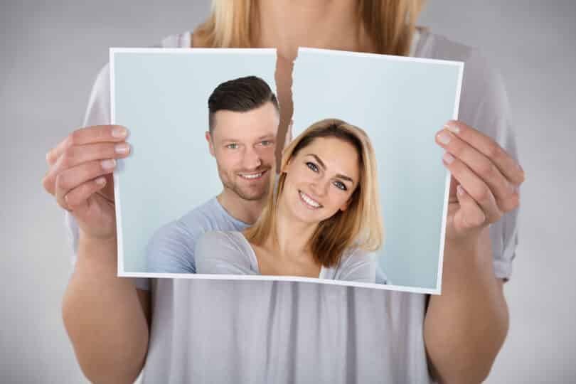 Uma mulher rasgando uma fotografia de um casal.