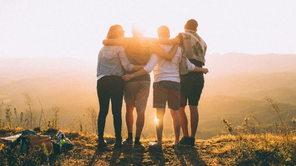 Pessoas se abraçando durante um pôr do sol.
