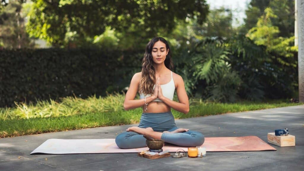 Uma mulher meditando ao ar livre.