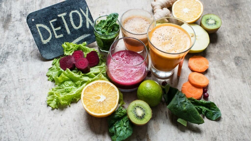 Sucos de várias frutas e vegetais diferentes. À esquerda, uma pequena placa na qual consta o texto "detox".