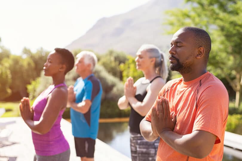 Várias pessoas meditando ao ar livre.