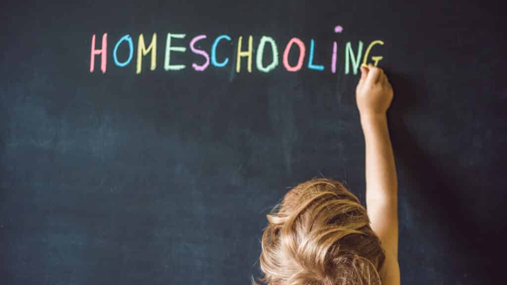 Criança escrevendo "homeschooling" em uma lousa