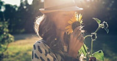 Uma mulher cheirando uma flor.