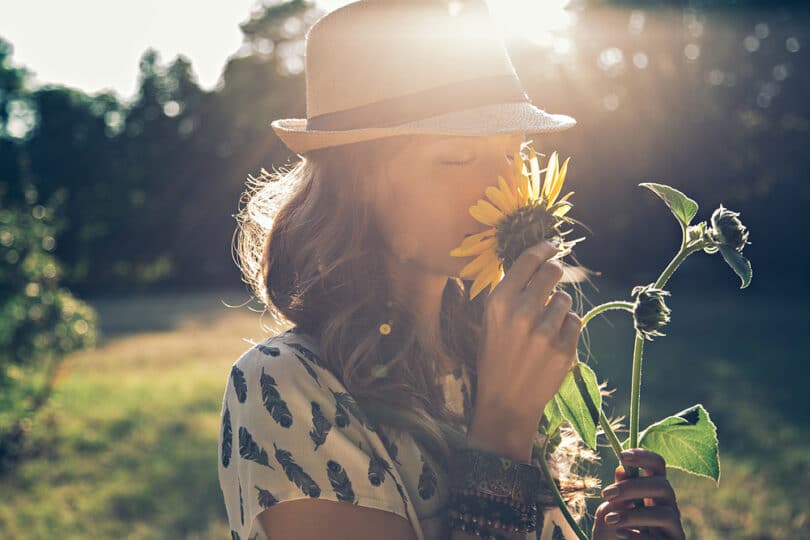 Uma mulher cheirando uma flor.