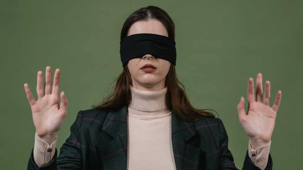 Uma mulher utilizando uma venda preta nos olhos.
