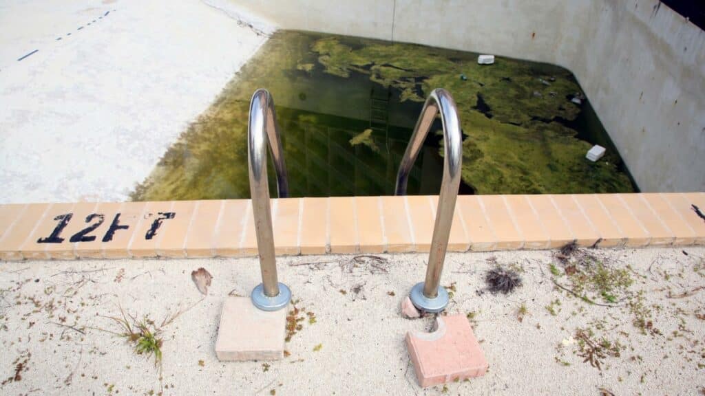 Uma piscina com pouca água. Esta está esverdeada.