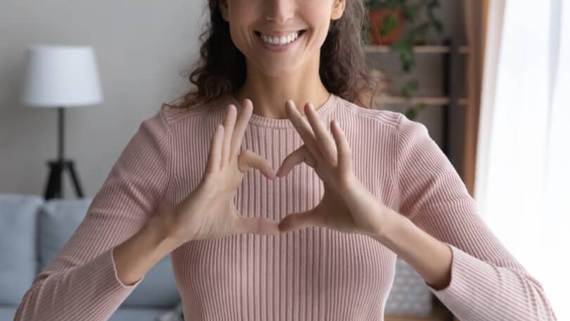 Uma mulher realizando um coração com as suas mãos.