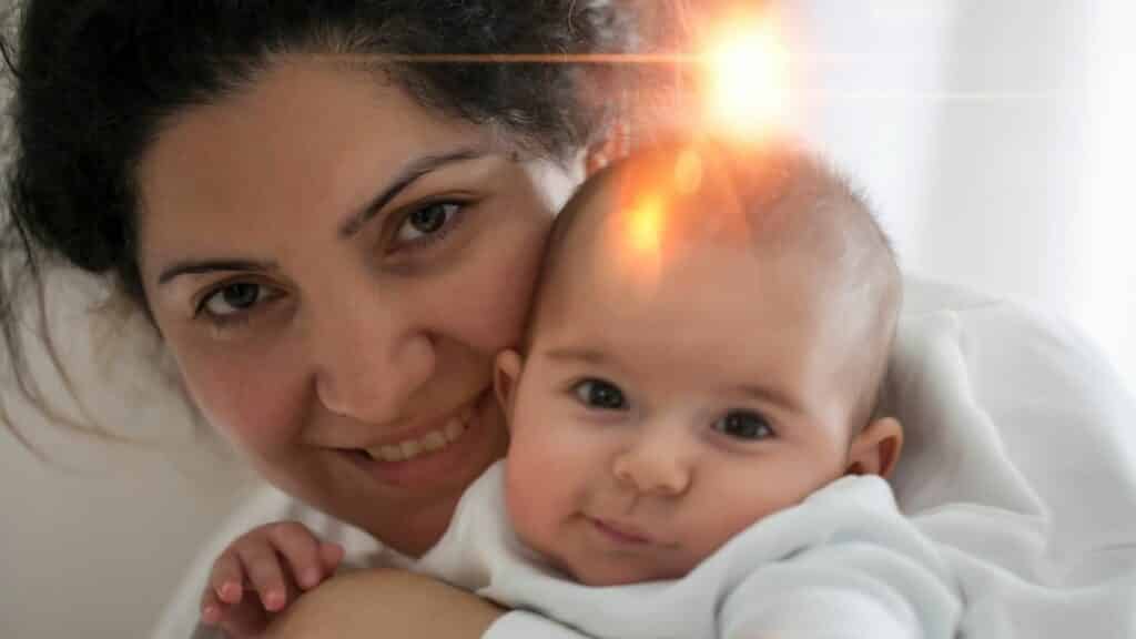 Uma mulher sorrindo ao lado de um pequeno bebê.