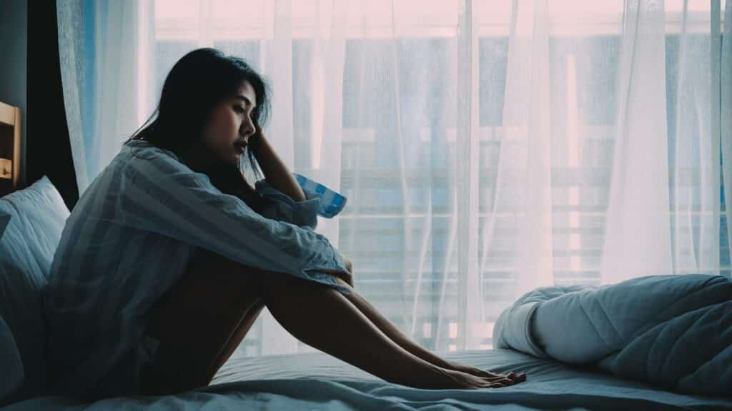 Uma mulher sentada numa cama.