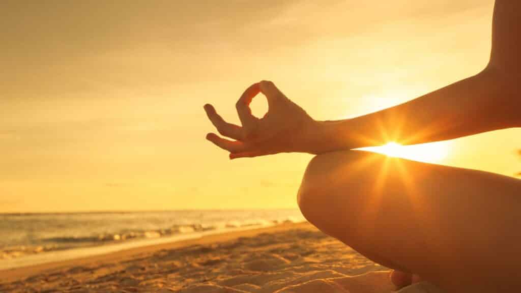 Uma pessoa meditando durante um poente ou nascer do sol.