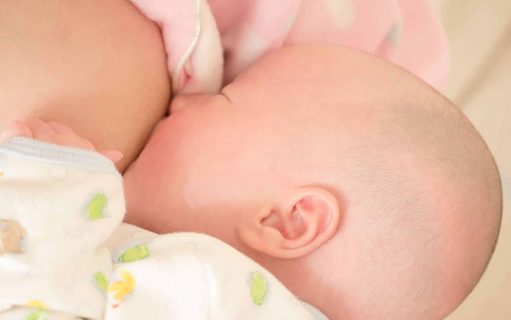 Um bebê sendo amamentado por uma mulher.