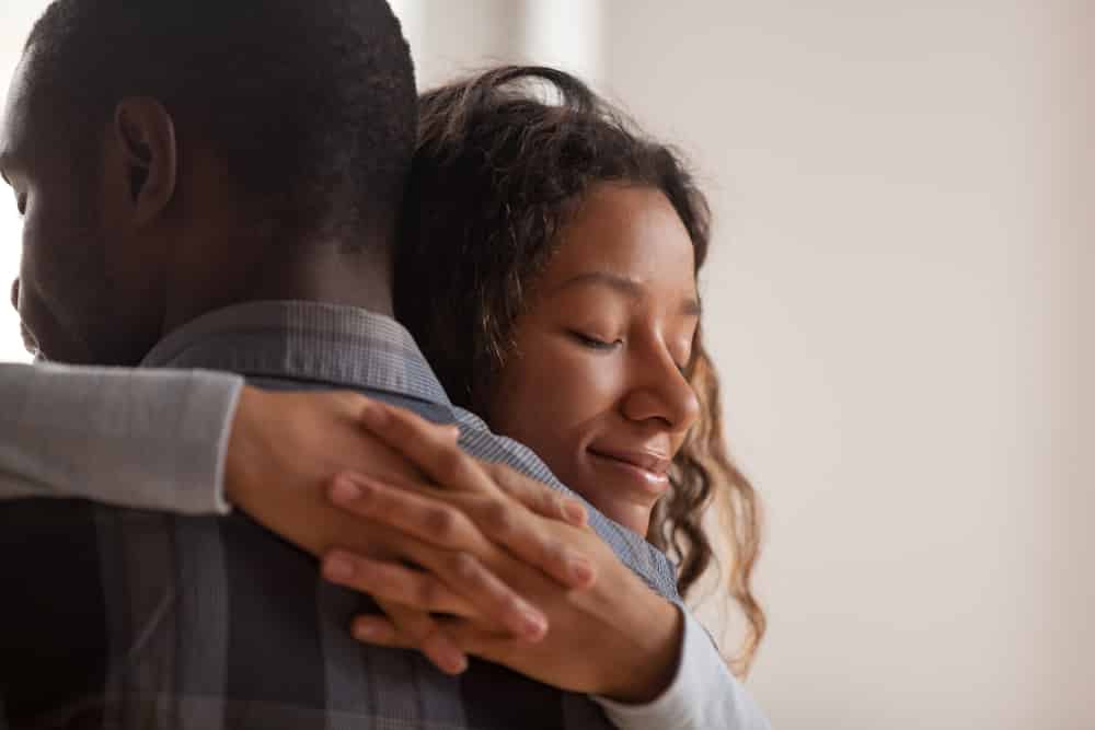 Homem e mulher negros se abraçando com cumplicidade