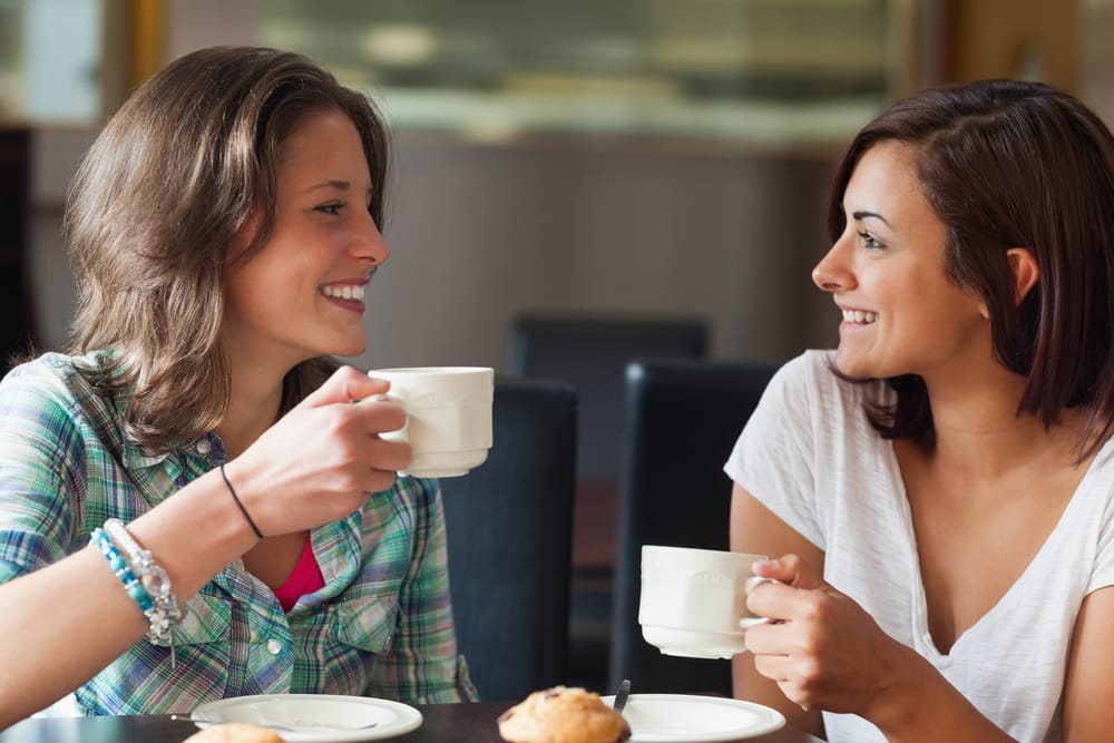 Duas mulheres brancas conversando e tomando um café