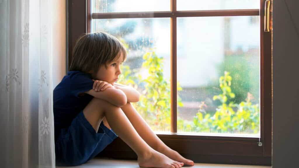 Uma criança sentada à beira de uma janela.