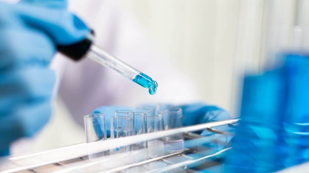 Um cientista de laboratório separando um líquido azul num frasco.