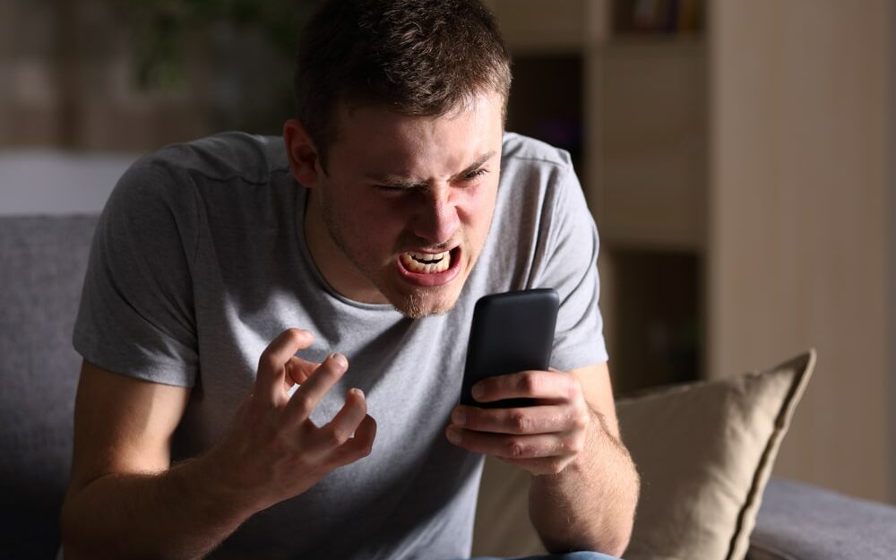 Um homem irado olhando a tela do seu celular.