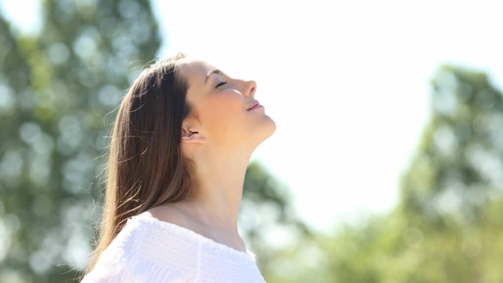 Uma mulher respirando e sorrindo.